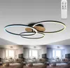 A ceiling lamp with multiple rings and a wood accent, shown in a living room setting with different lighting conditions. Produktbild-Vorschau