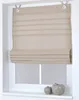 A beige Roman blind is shown hanging in a white window frame, with two decorative ceramic apples on the windowsill below. Produktbild-Vorschau