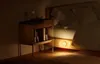 A bedside table with books next to a bed, with a soft light emanating from under the bed frame. Podgląd zdjęcia produktu