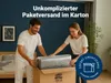 A couple is unboxing a mattress from a cardboard box in a bedroom. Produktbild-Vorschau