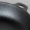 A close-up view of the textured surface and handle of a black cast iron pan. Produktbild-Vorschau