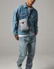 A man wearing a denim jacket and jeans, carrying a crossbody bag. Anteprima dell’immagine prodotto