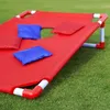 A red cornhole game board with blue and red bean bags on a green grassy lawn. Podgląd zdjęcia produktu