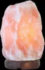 A Himalayan salt lamp on a wooden base against a black background. Produktbild-Vorschau