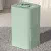 A mint green air purifier sits on a gray rug in a room with soft lighting. Produktbild-Vorschau