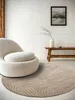 A modern living room scene featuring a round rug and a comfortable armchair. Anteprima dell’immagine prodotto