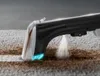 A close-up of a carpet cleaner spraying water onto a dirty carpet. Produktbild-Vorschau