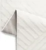 A close-up view of a white rug with a geometric pattern, folded to show the underside. Anteprima dell’immagine prodotto