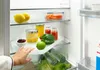 A hand reaching into a refrigerator to grab a rotating tray with food items. Anteprima dell’immagine prodotto