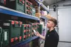 A man in a warehouse is using his phone to scan a product on a shelf. Voir les images du produit