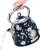 A hand holding a floral patterned electric kettle as water is poured from its spout. Produktbild-Vorschau