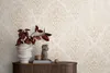 A close-up of a wooden cabinet with decorative items on top, against a patterned wallpaper. Produktbild-Vorschau