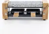 A close-up, studio shot of a two-person raclette grill with a granite stone top and wooden accents, against a white background. Produktbild-Vorschau