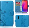 A collage of images showing a blue flip phone case with a floral and butterfly design, including a view of the case open with cards and money inserted, and a view of the back of the case showing the camera cutout. Produktbild-Vorschau