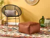 A modern living room scene with a black rattan chair, a brown pouf, a patterned rug, and decorative glass bottles. Náhled obrázku produktu