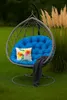 A hanging egg chair with a blue cushion and a floral pillow sits on a green lawn next to tall, feathery grass. Anteprima dell’immagine prodotto