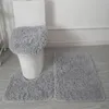 A set of three fluffy gray bath mats are arranged on a light gray wooden floor in front of a white toilet. Anteprima dell’immagine prodotto
