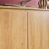 A close-up view of a wooden sideboard with two doors, a book, and a decorative vase on top. Produktbild-Vorschau