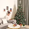 A man is sitting on a couch reading a book next to a decorated Christmas tree. Produktbild-Vorschau