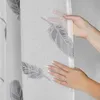 A close-up shot of a hand holding a sheer curtain with a feather pattern. Produktbild-Vorschau