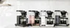 A line of Moccacoffee makers on a countertop with a tiled backsplash. Náhľad obrázku produktu