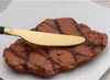 A close-up shot of a grilled steak on a white plate with a gold and black knife resting on top. Produktbild-Vorschau