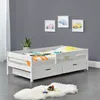 A white wooden children's bed with drawers and a colorful duvet cover is shown in a room with gray walls and framed car pictures. Náhľad obrázku produktu