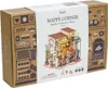 The image shows the product packaging for a miniature house building kit, specifically "Emily's Flower Shop". The packaging features illustrations of the finished product and decorative elements related to a flower shop and fruit shop. Náhled obrázku produktu