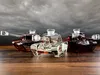 Three glass decanters shaped like tanks, filled with different colored liquids, sit on a wooden surface against a stormy sky. Podgląd zdjęcia produktu