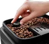 A hand is adjusting a dial on a coffee grinder filled with coffee beans. Voir les images du produit