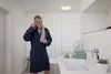 A man in a bathrobe is in a modern bathroom, drying his face with a towel. Produktbild-Vorschau
