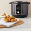 An Instant Pot Duo Crisp multicooker is shown next to a plate of fried food. Produktbild-Vorschau
