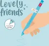 A hand holding a blue pen with a bunny charm, writing on a light blue background. Podgląd zdjęcia produktu