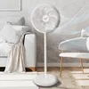 A white standing fan in a modern living room next to a sofa and a chair. Podgląd zdjęcia produktu