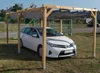 A white car is parked under a wooden carport with a gray fabric roof. Produktbild-Vorschau