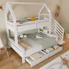 A white wooden bunk bed with a house-shaped frame, stairs, and drawers, set up in a child's bedroom with toys and bedding. Produktbild-Vorschau