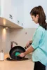 A woman is washing a frying pan in a kitchen sink. Anteprima dell’immagine prodotto