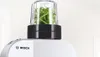 A close-up shot of a Bosch food processor attachment filled with green herbs. Podgląd zdjęcia produktu