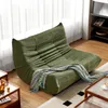 A green sofa is placed in a well-lit room with sheer curtains and wooden flooring. Produktbild-Vorschau