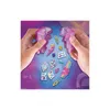 Hands holding purple crystal-like objects with small accessories scattered around. Náhled obrázku produktu