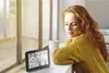 A woman with red hair is looking at a weather station display on a table by a window. Anteprima dell’immagine prodotto