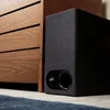 A Polk Audio soundbar and subwoofer are placed next to a wooden cabinet. Produktbild-Vorschau
