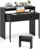 A black desk with a laptop, headphones, and a plant on it, with a smaller black unit in front. Náhled obrázku produktu