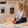 A toddler playing with a wooden toy kitchen set and cutting food toys. Náhľad obrázku produktu