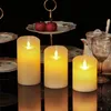 Three LED candles are arranged on a reflective surface, with a tiered serving stand holding two red apples in the background. Podgląd zdjęcia produktu