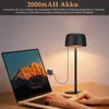 A black LED desk lamp is shown charging via a USB-C cable connected to a laptop, with a person's hands typing on the laptop. Produktbild-Vorschau