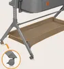 A close-up view of the lower part of a baby crib, showing its legs, wheels, and storage basket. Produktbild-Vorschau