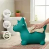 A green inflatable dinosaur toy is being wiped with a cloth in a bathroom setting. Podgląd zdjęcia produktu