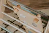 Close-up of a wooden climbing triangle with pastel-colored rungs and climbing holds. Voir les images du produit