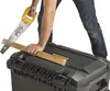 A person is using a hand saw to cut a piece of wood resting on a black toolbox. Anteprima dell’immagine prodotto